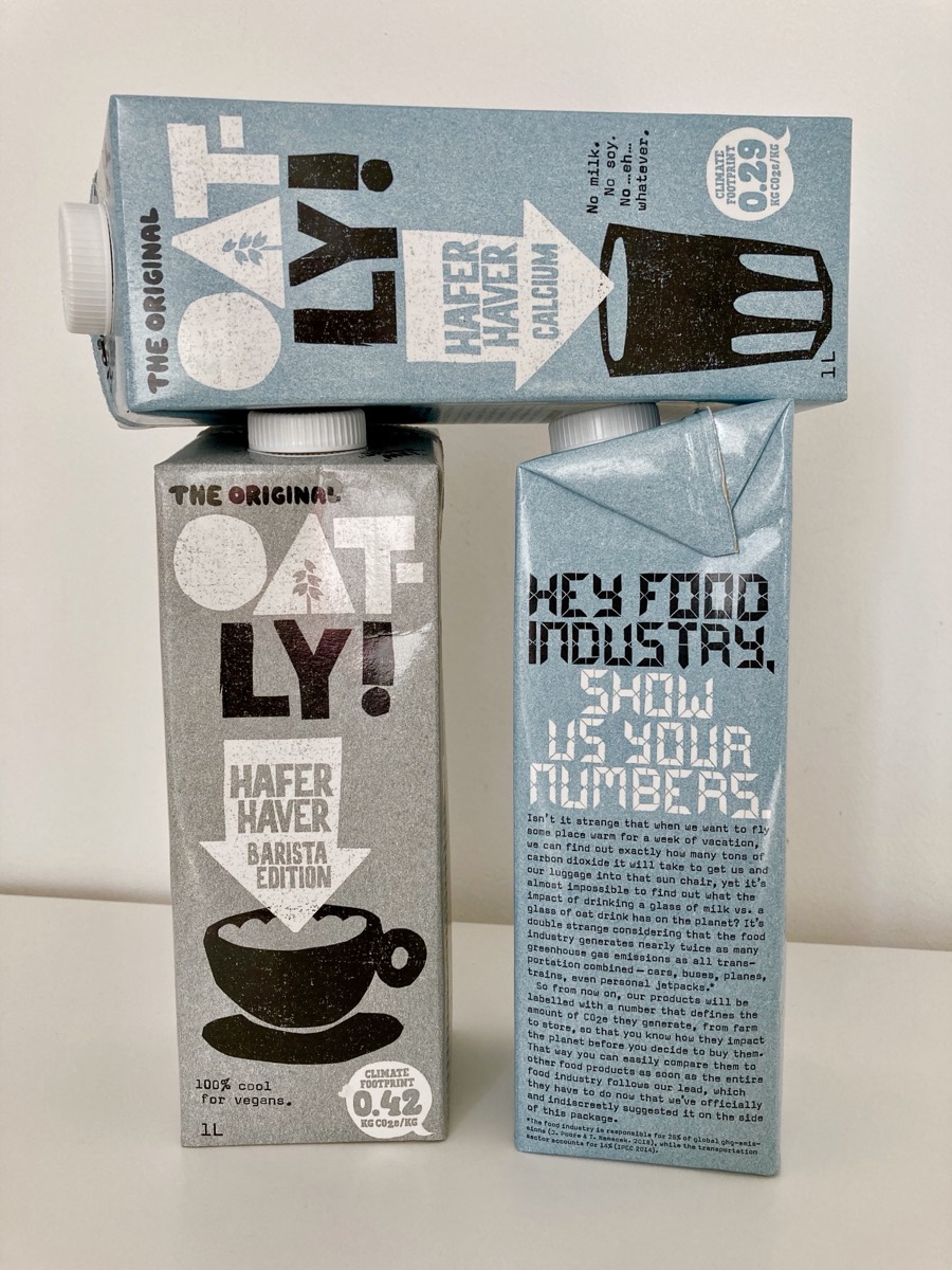 Three Oatly cartons, one printed with a long open letter headed Hey food industry, show us your numbers